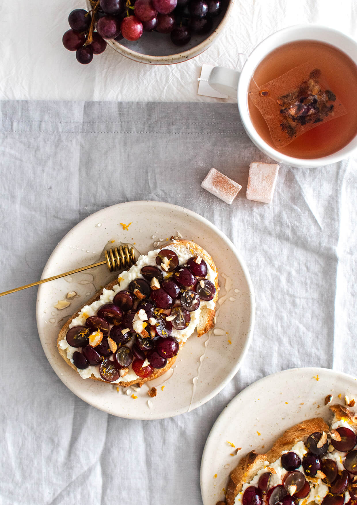 breakfast table setting with toast on plates, grapes and cup of tea