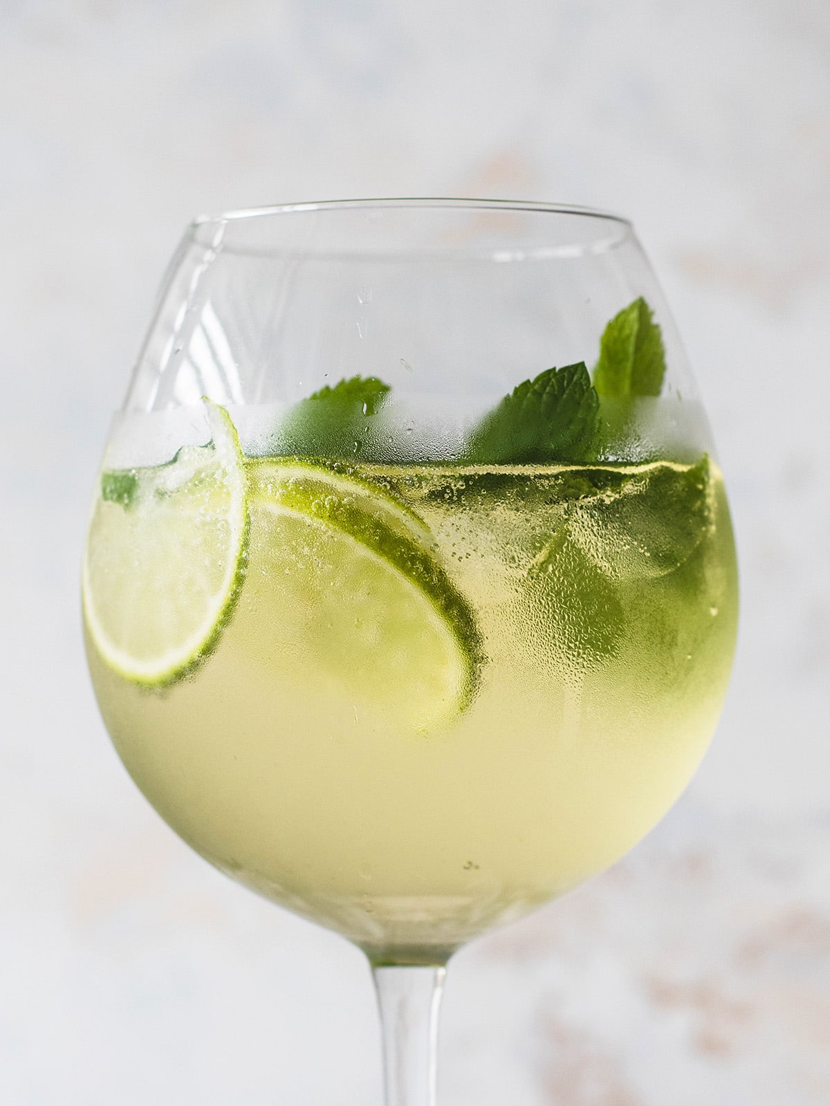 white wine cocktail in a glass with lime slices and mint