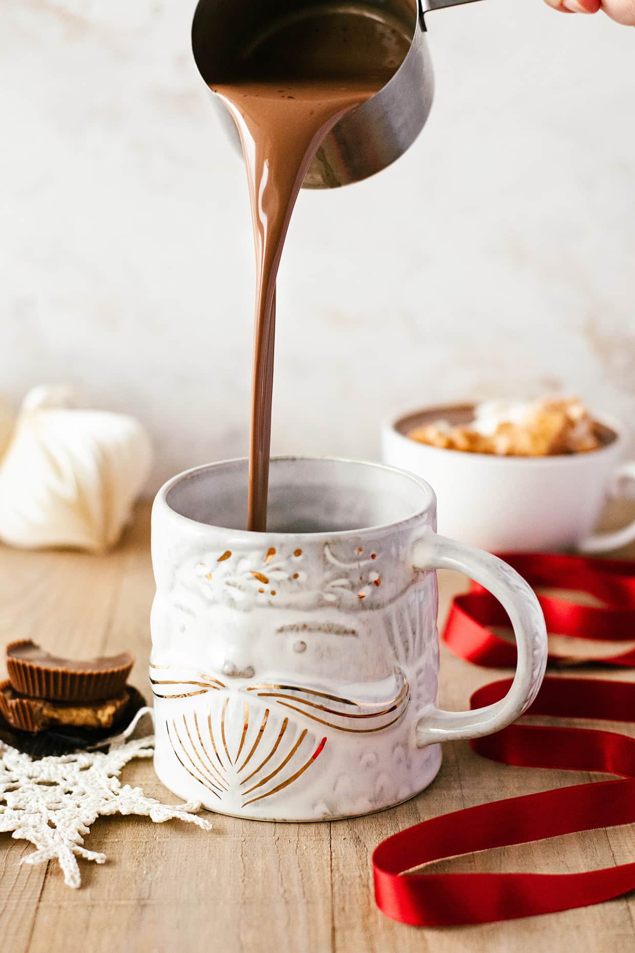 pouring hot chocolate in a white santa mug 