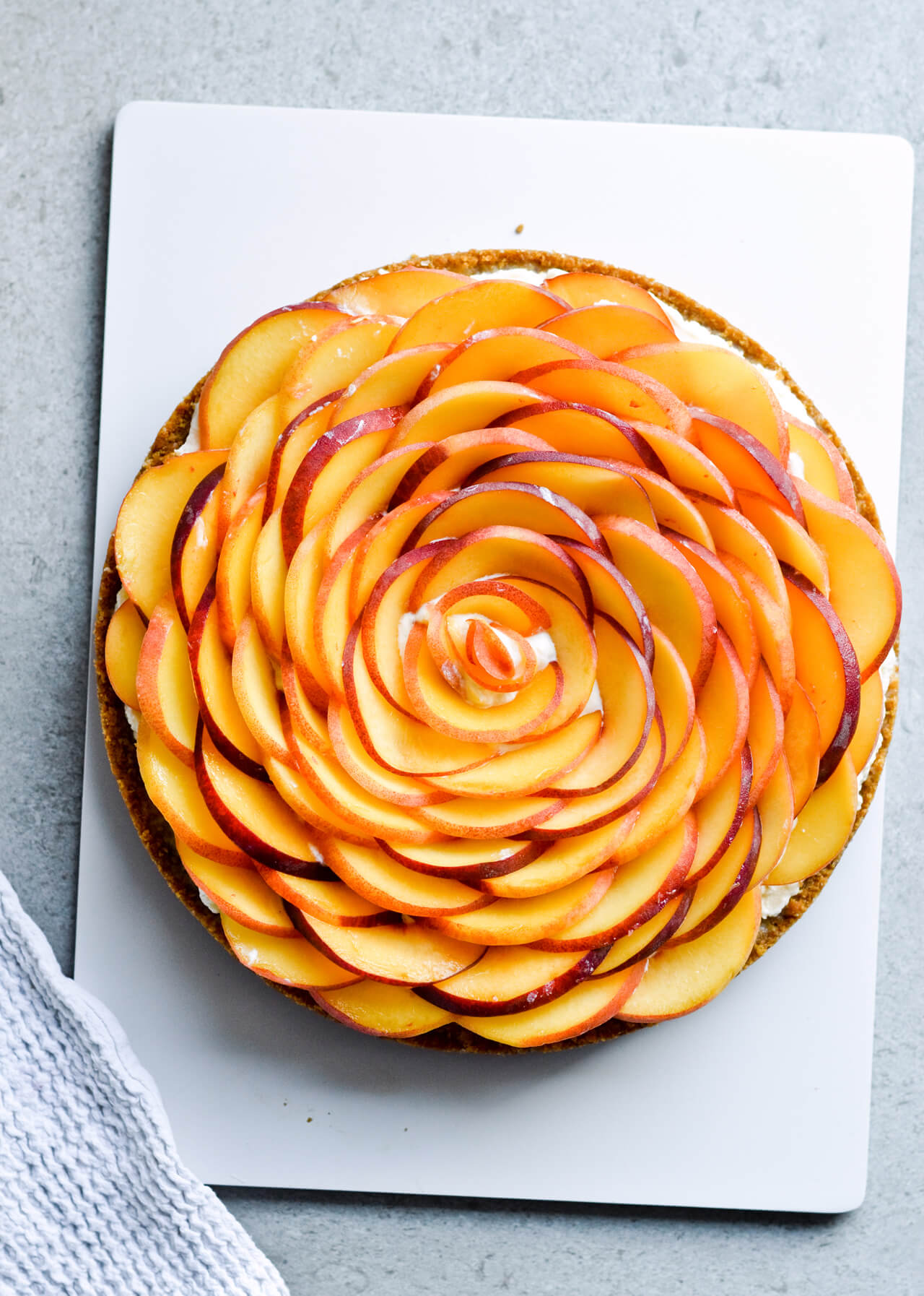 Whipped mascarpone peach tart - crumbly cookie crust filled with vanilla whipped mascarpone and topped with fresh peaches shaped like a rose! A truly impressive dessert. | sugarsalted.com