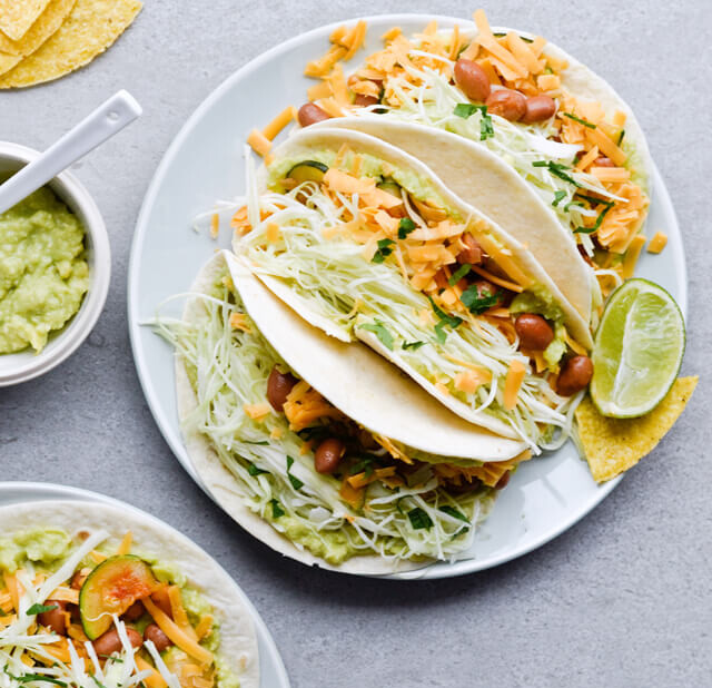 Guacamole cabbage bean tacos are the best vegetarian tacos! With easy homemade guacamole, zesty cabbage, zucchini, paprika beans and lots of cheddar! | sugarsalted.com