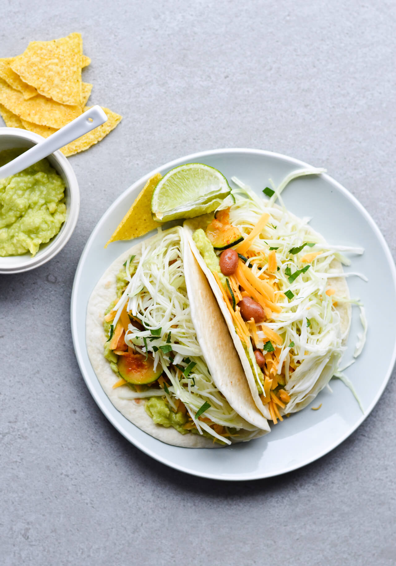 Guacamole cabbage bean tacos are the best vegetarian tacos! With easy homemade guacamole, zesty cabbage, zucchini, paprika beans and lots of cheddar! | sugarsalted.com