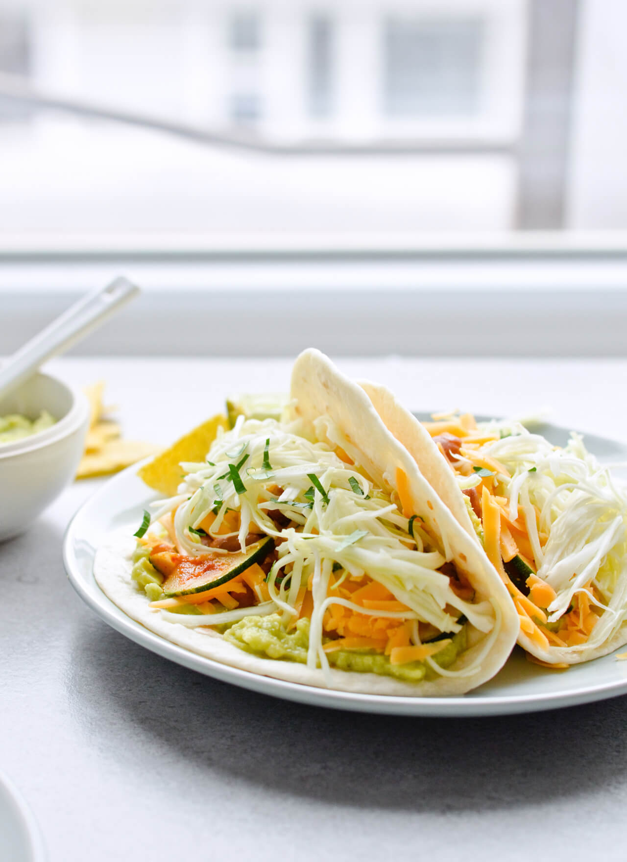 Guacamole cabbage bean tacos are the best vegetarian tacos! With easy homemade guacamole, zesty cabbage, zucchini, paprika beans and lots of cheddar! | sugarsalted.com