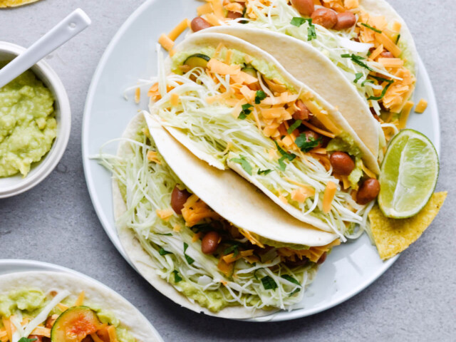 Guacamole cabbage bean tacos are the best vegetarian tacos! With easy homemade guacamole, zesty cabbage, zucchini, paprika beans and lots of cheddar! | sugarsalted.com