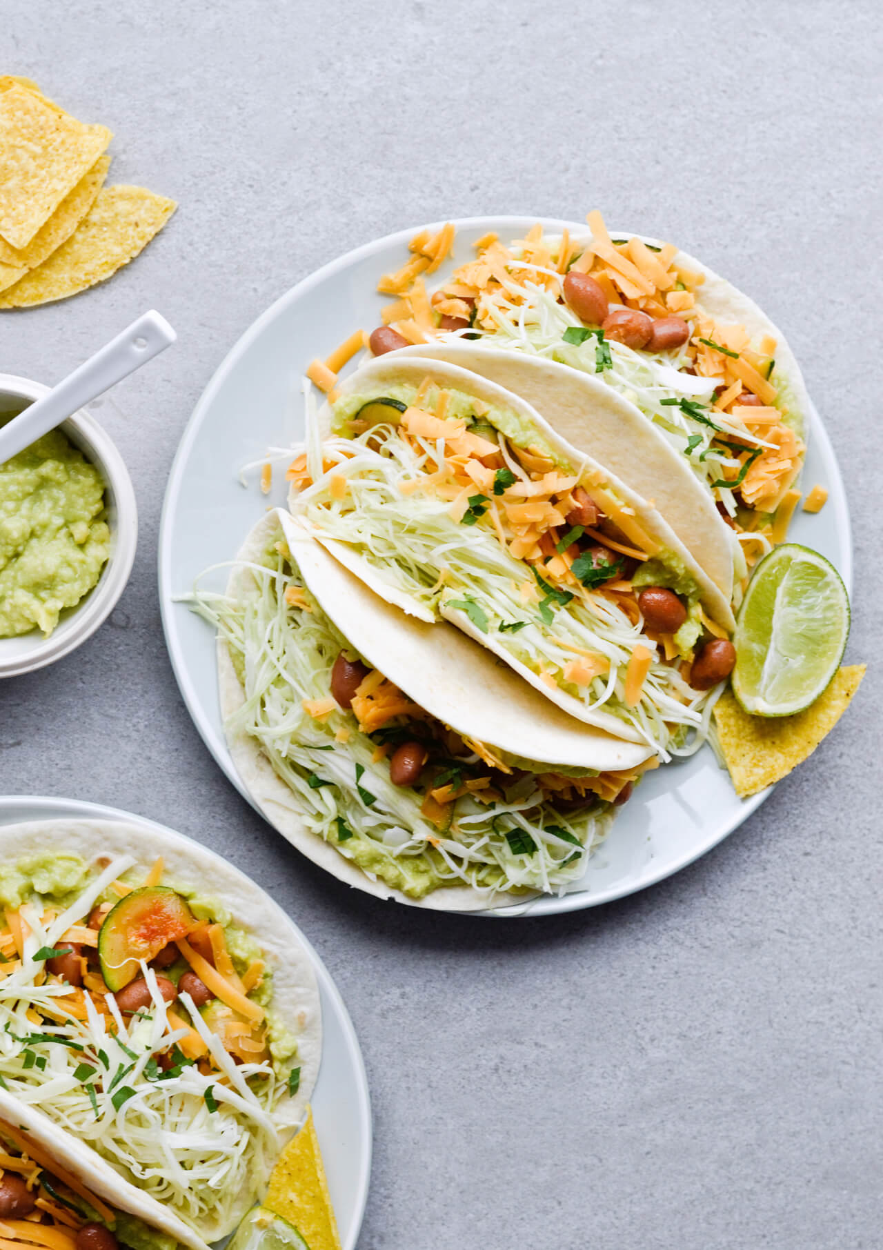 Guacamole cabbage bean tacos are the best vegetarian tacos! With easy homemade guacamole, zesty cabbage, zucchini, paprika beans and lots of cheddar! | sugarsalted.com