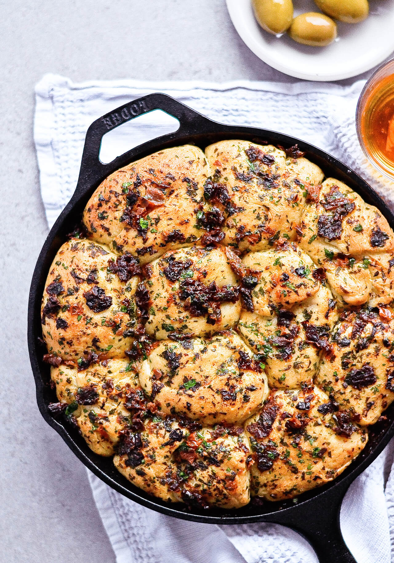 Recipe for sun-dried tomato herb skillet rolls. Dough infused with oregano and rolls drenched with parsley butter and sun-dried tomatoes. Soft, individual rolls straight from the skillet, great for the holiday dinner table. | sugarsalted.com