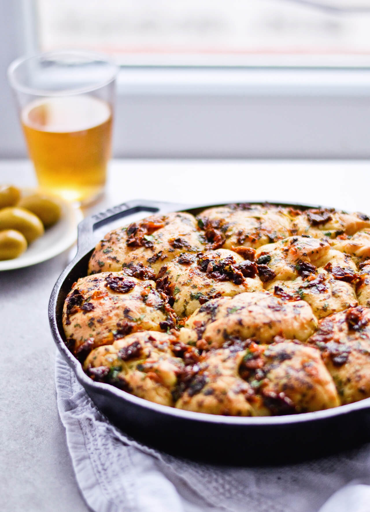 Recipe for sun-dried tomato herb skillet rolls. Dough infused with oregano and rolls drenched with parsley butter and sun-dried tomatoes. Soft, individual rolls straight from the skillet, great for the holiday dinner table. | sugarsalted.com