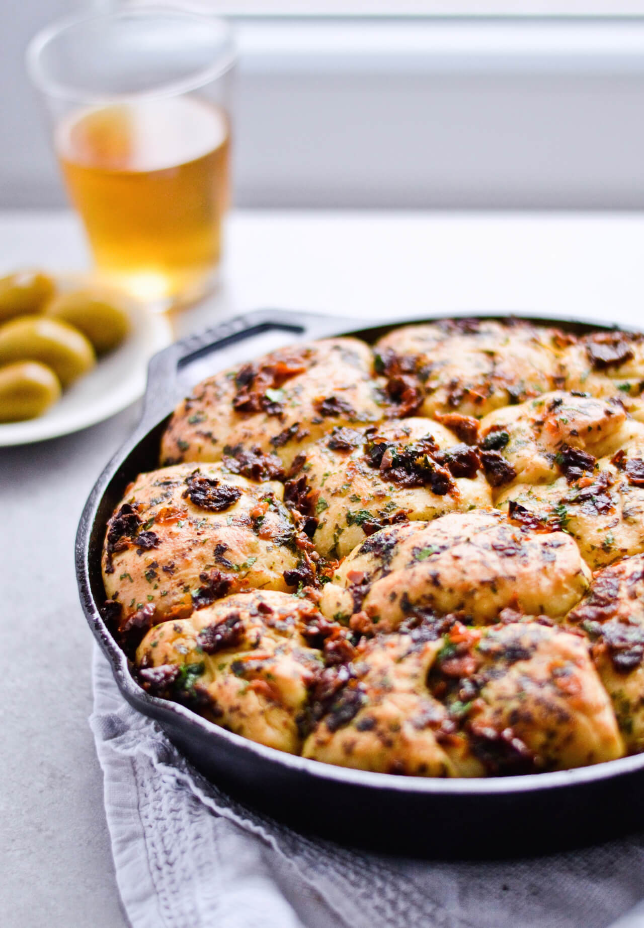 Recipe for sun-dried tomato herb skillet rolls. Dough infused with oregano and rolls drenched with parsley butter and sun-dried tomatoes. Soft, individual rolls straight from the skillet, great for the holiday dinner table. | sugarsalted.com