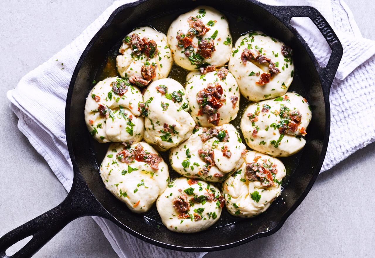 Recipe for sun-dried tomato herb skillet rolls. Dough infused with oregano and rolls drenched with parsley butter and sun-dried tomatoes. Soft, individual rolls straight from the skillet, great for the holiday dinner table. | sugarsalted.com