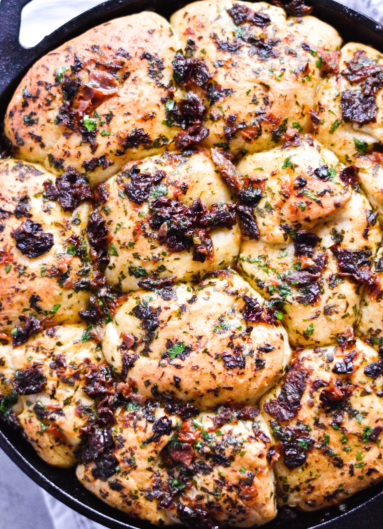 Recipe for sun-dried tomato herb skillet rolls. Dough infused with oregano and rolls drenched with parsley butter and sun-dried tomatoes. Soft, individual rolls straight from the skillet, great for the holiday dinner table. | sugarsalted.com