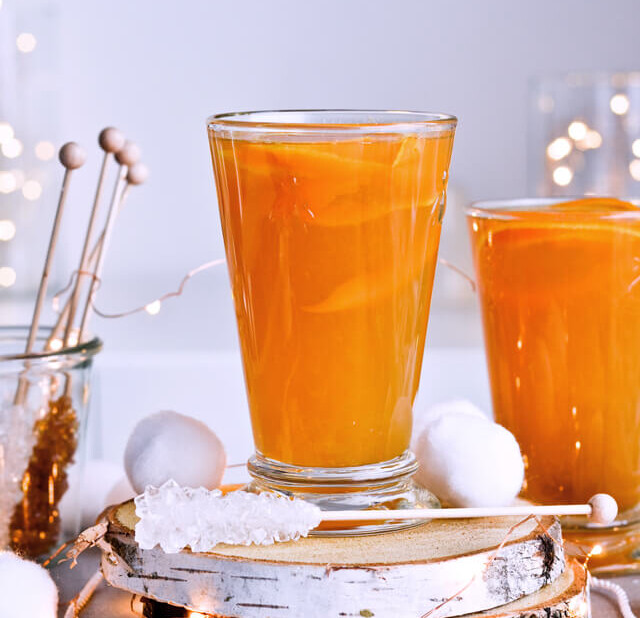 Recipe for Winter tea rum punch, the perfect winter cozy drink! Made with orange juice, honey, ginger beer and cinnamon baked apple teas! Served with orange twists and sugar swizzle sticks. A great cocktail made in 15 minutes! | @mitzyathome sugarsalted.com