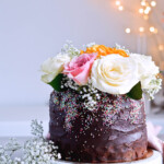 Recipe for Chocolate lover's triple chocolate ganache layer cake, every chocoholic's dream come true! Made with coffee, rich bittersweet chocolate and cream, but no butter, this chocolate cake is smooth and addicting! Topped with sprinkles and flowers, to make it super pretty. | sugarsalted.com