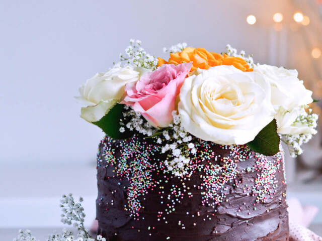 Recipe for Chocolate lover's triple chocolate ganache layer cake, every chocoholic's dream come true! Made with coffee, rich bittersweet chocolate and cream, but no butter, this chocolate cake is smooth and addicting! Topped with sprinkles and flowers, to make it super pretty. | sugarsalted.com