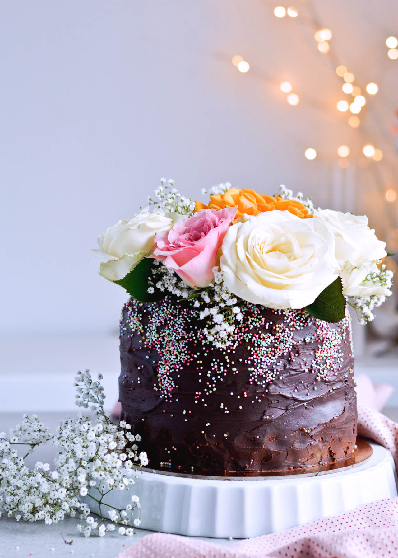 Recipe for Chocolate lover's triple chocolate ganache layer cake, every chocoholic's dream come true! Made with coffee, rich bittersweet chocolate and cream, but no butter, this chocolate cake is smooth and addicting! Topped with sprinkles and flowers, to make it super pretty. | sugarsalted.com
