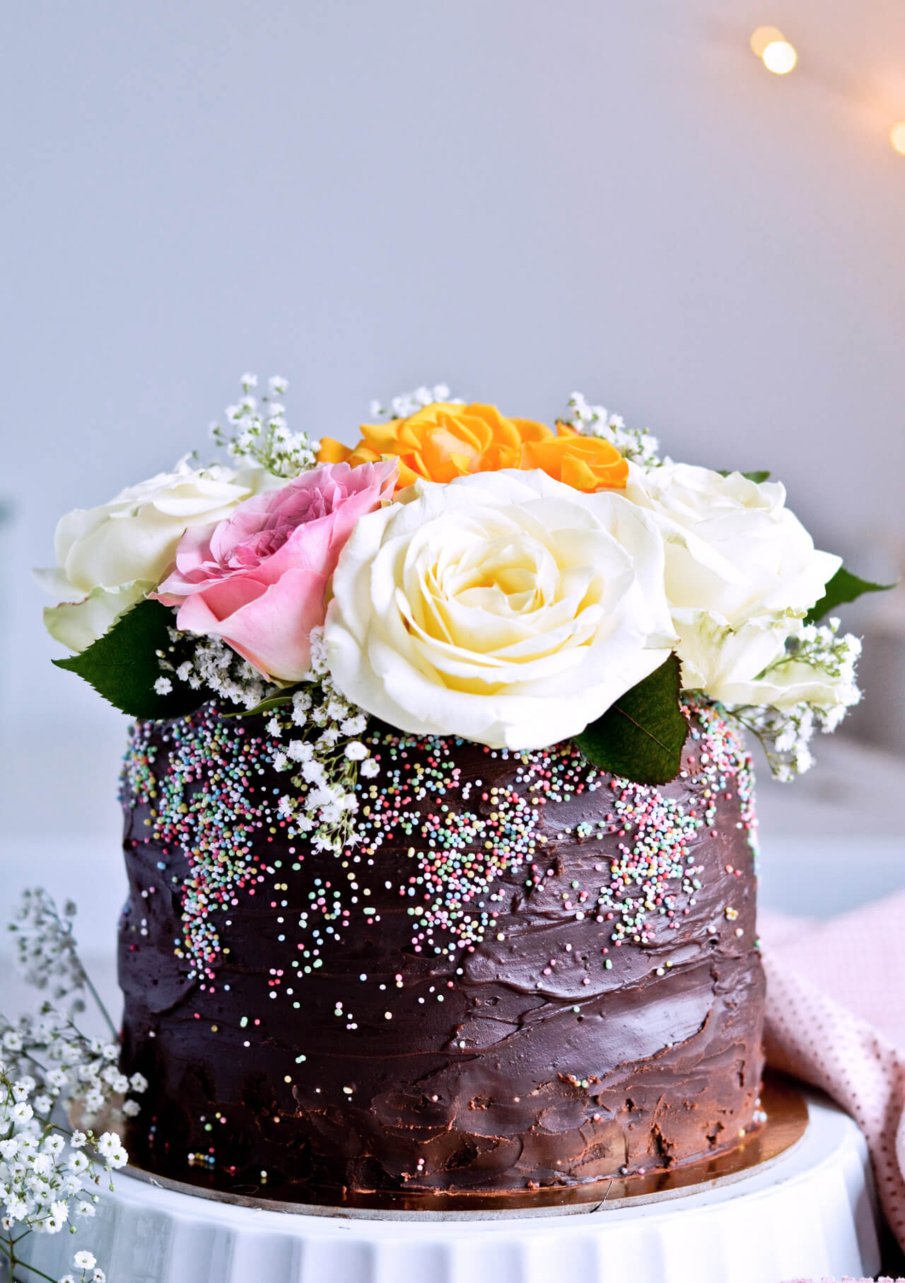 Recipe for Chocolate lover's triple chocolate ganache layer cake, every chocoholic's dream come true! Made with coffee, rich bittersweet chocolate and cream, but no butter, this chocolate cake is smooth and addicting! Topped with sprinkles and flowers, to make it super pretty. | sugarsalted.com