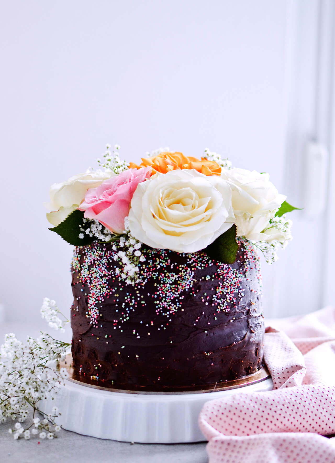 Recipe for Chocolate lover's triple chocolate ganache layer cake, every chocoholic's dream come true! Made with coffee, rich bittersweet chocolate and cream, but no butter, this chocolate cake is smooth and addicting! Topped with sprinkles and flowers, to make it super pretty. | sugarsalted.com