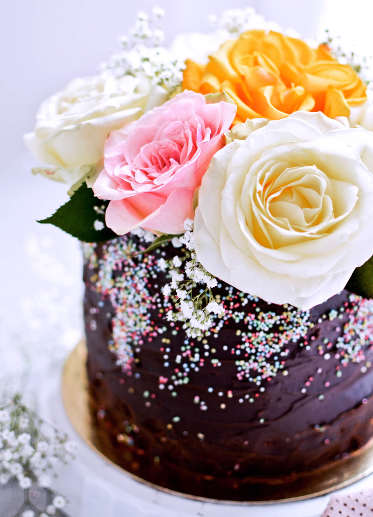 Recipe for Chocolate lover's triple chocolate ganache layer cake, every chocoholic's dream come true! Made with coffee, rich bittersweet chocolate and cream, but no butter, this chocolate cake is smooth and addicting! Topped with sprinkles and flowers, to make it super pretty. | sugarsalted.com