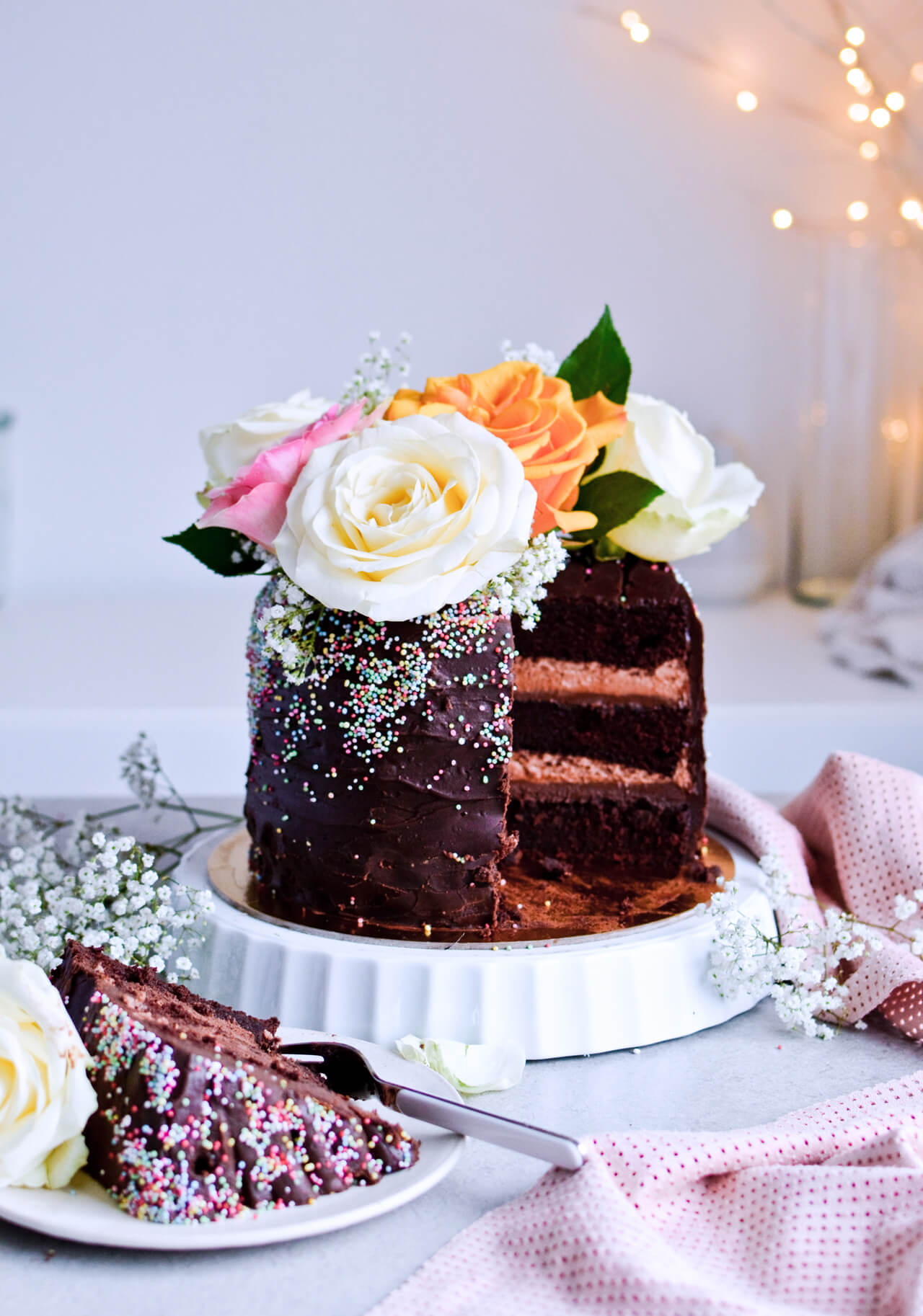 Recipe for Chocolate lover's triple chocolate ganache layer cake, every chocoholic's dream come true! Made with coffee, rich bittersweet chocolate and cream, but no butter, this chocolate cake is smooth and addicting! Topped with sprinkles and flowers, to make it super pretty. | sugarsalted.com
