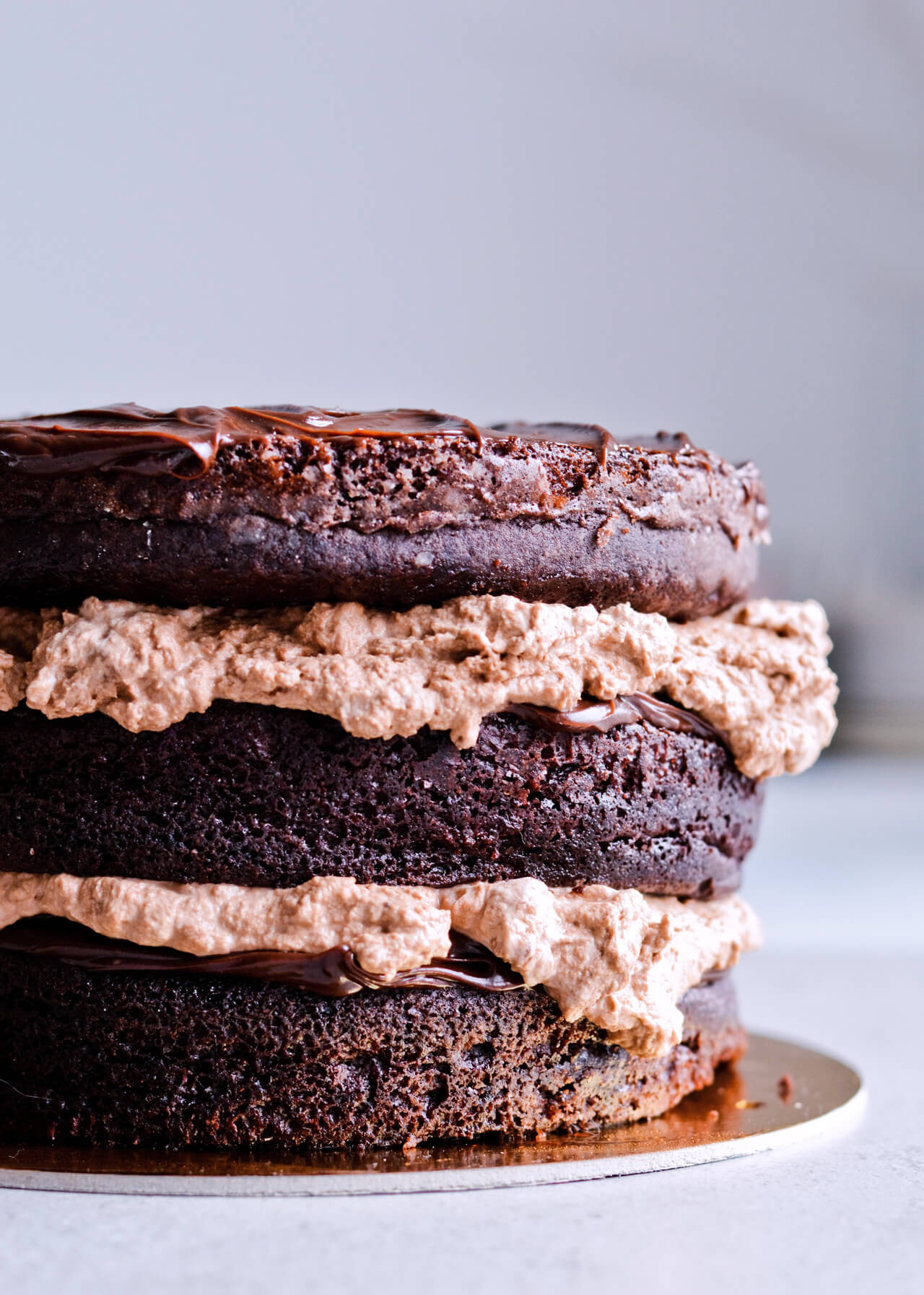 Recipe for Chocolate lover's triple chocolate ganache layer cake, every chocoholic's dream come true! Made with coffee, rich bittersweet chocolate and cream, but no butter, this chocolate cake is smooth and addicting! Topped with sprinkles and flowers, to make it super pretty. | sugarsalted.com