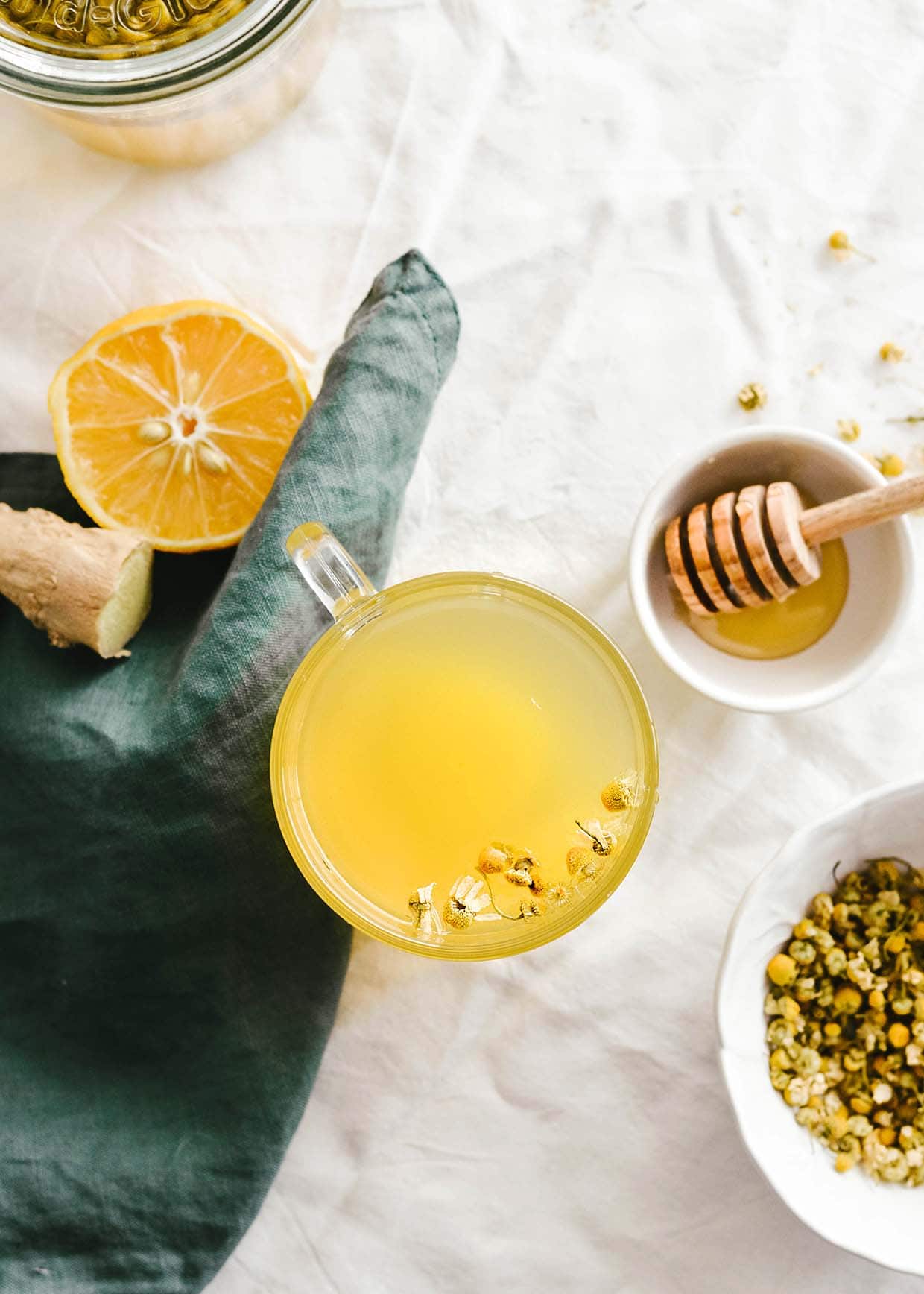 top view of table with chamomile tea in glass mug, honey, citrus, ginger,