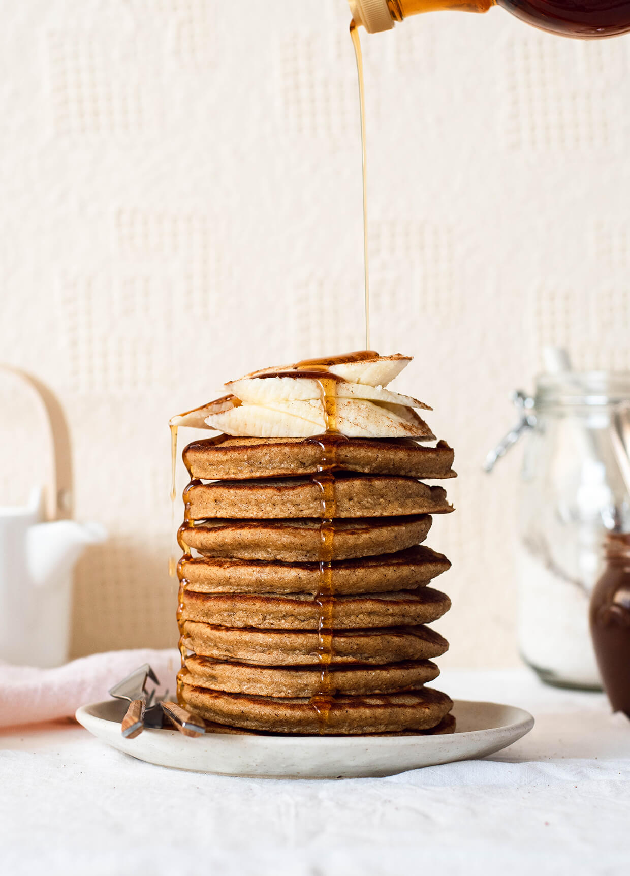 a stack of banana pancakes topped with sliced banana and maple syrup