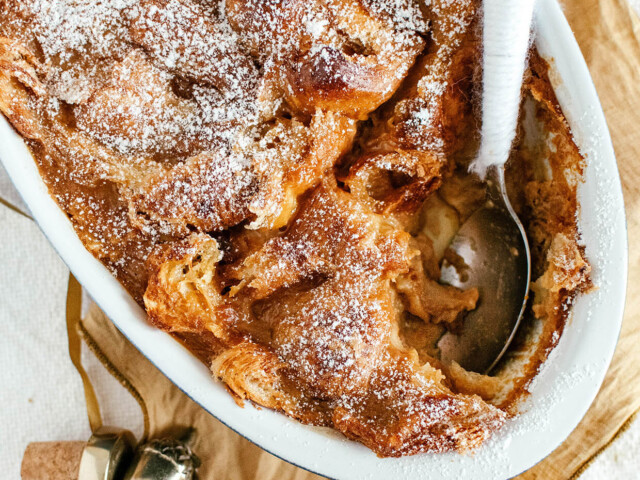 oval baking dish with bread pudding, spoon inside,