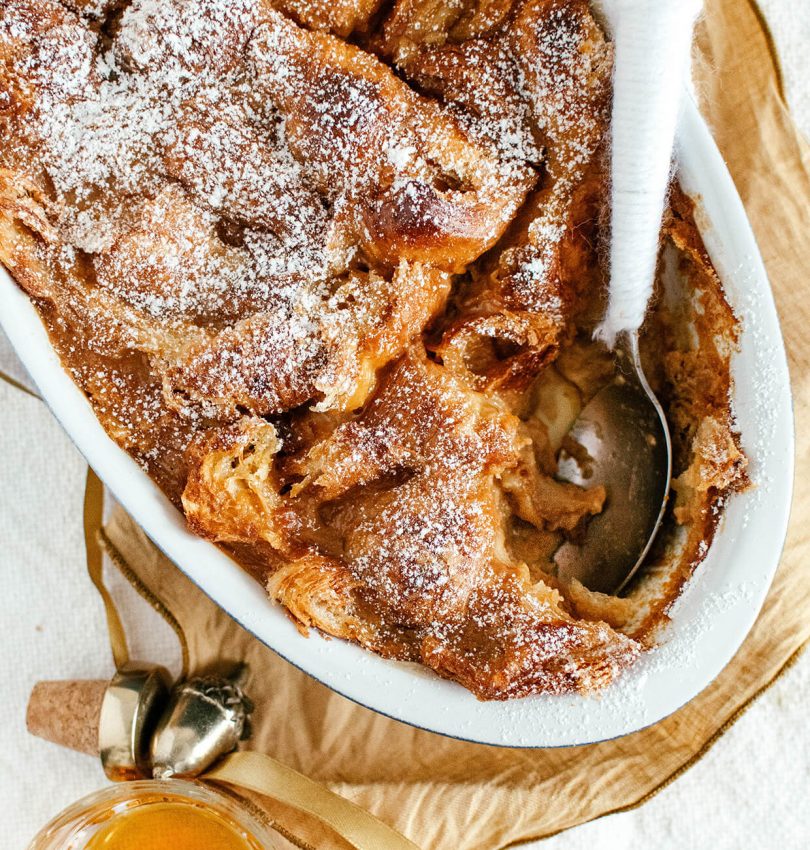 oval baking dish with bread pudding, spoon inside,