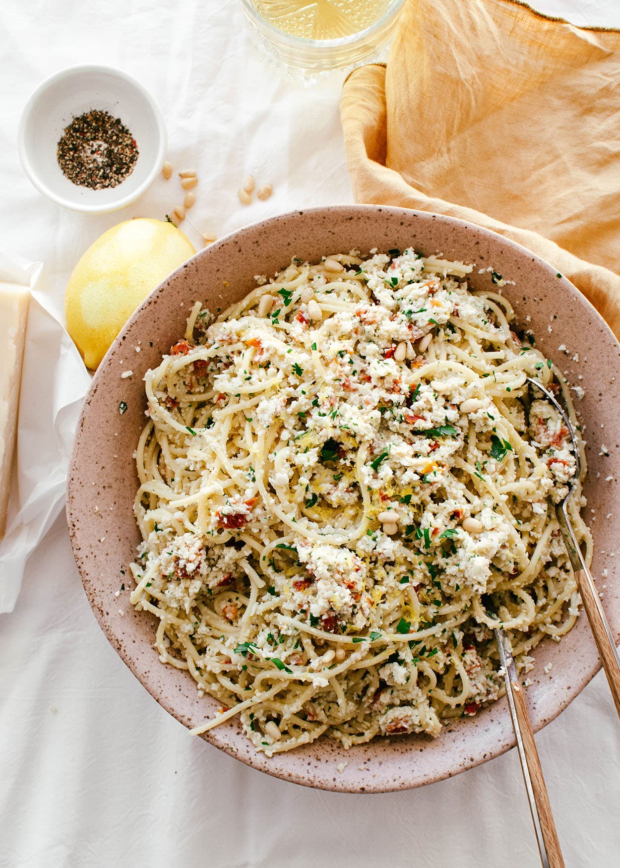 cooked spaghetti mixed with raw cauliflower pesto in large bowl