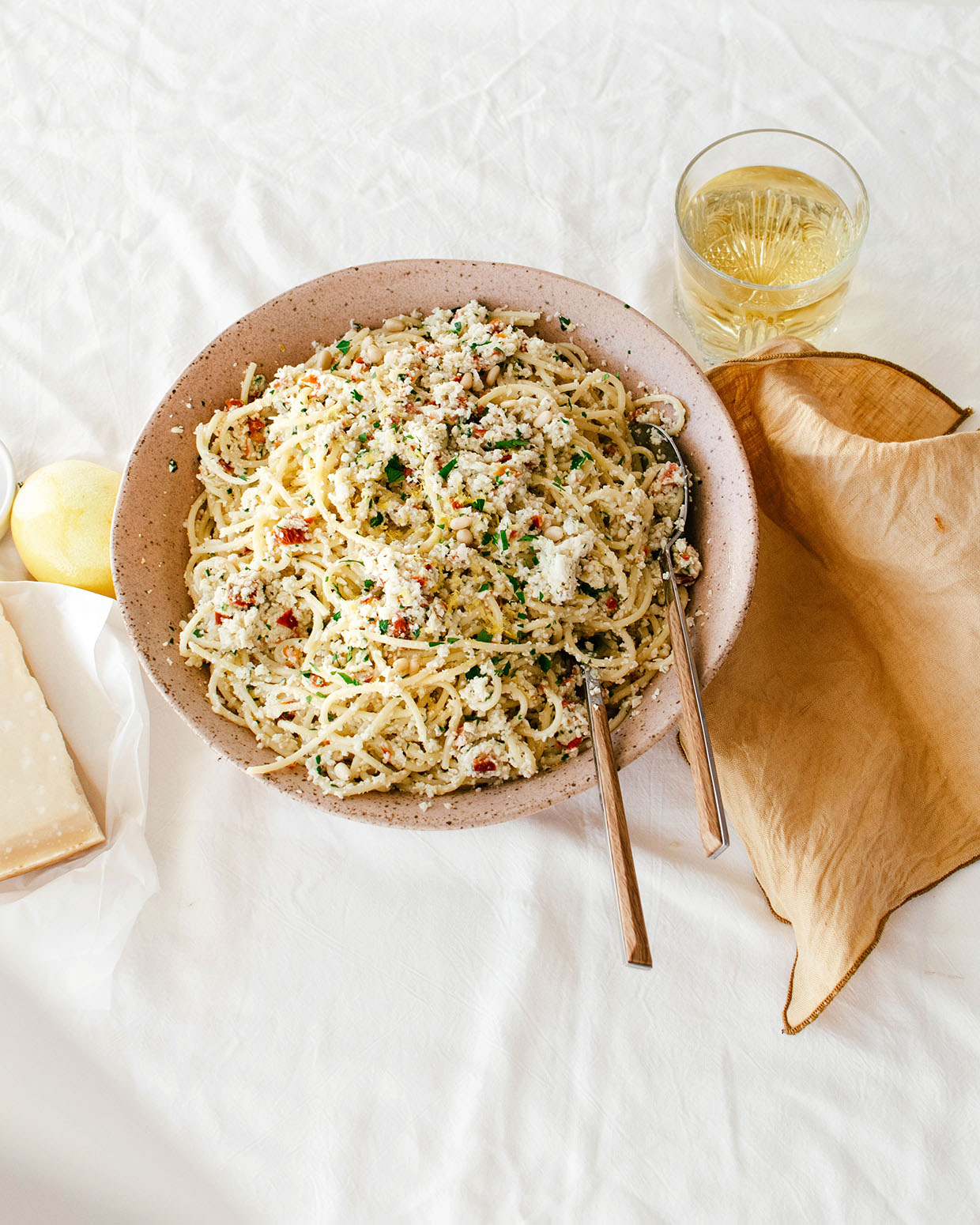 table setting with a bowl of spaghetti, wine, cheese and lemon