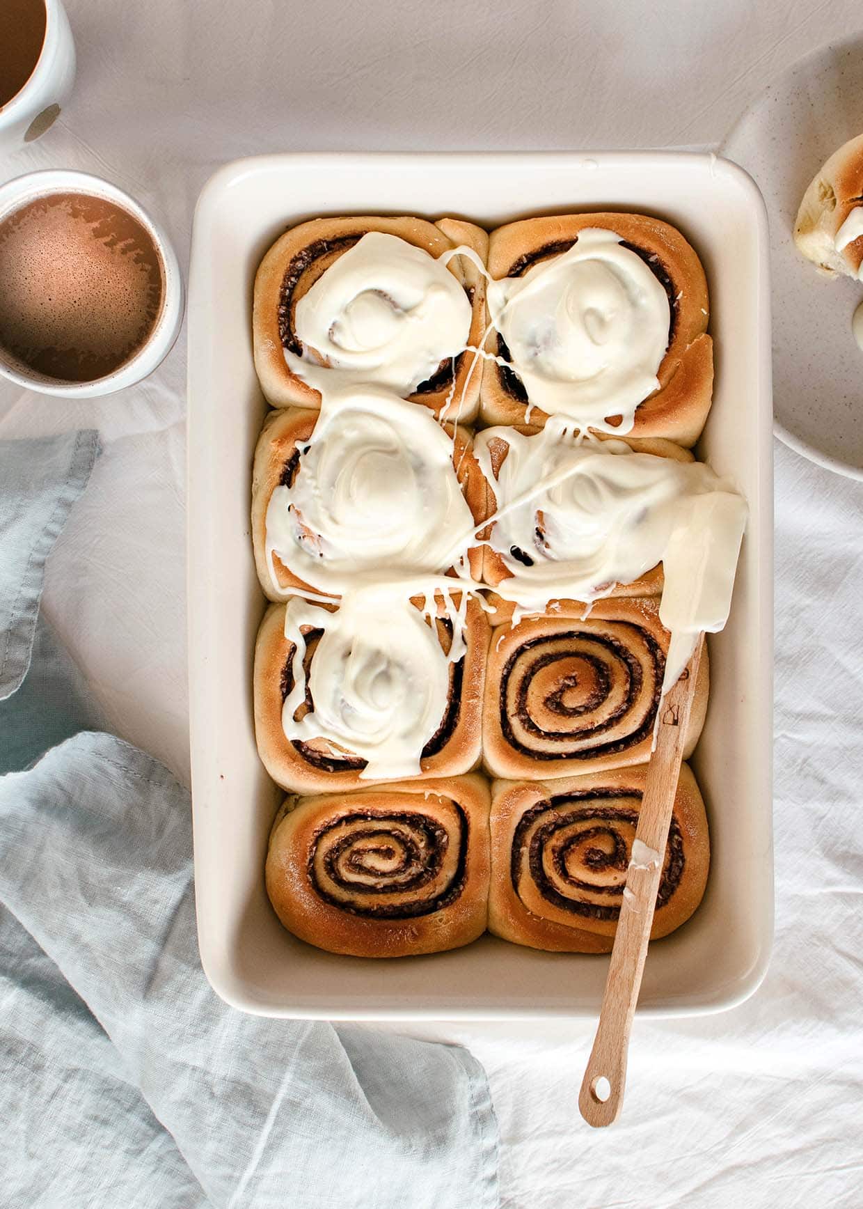 cinnamon rolls in baking pan with white chocolate glaze on top