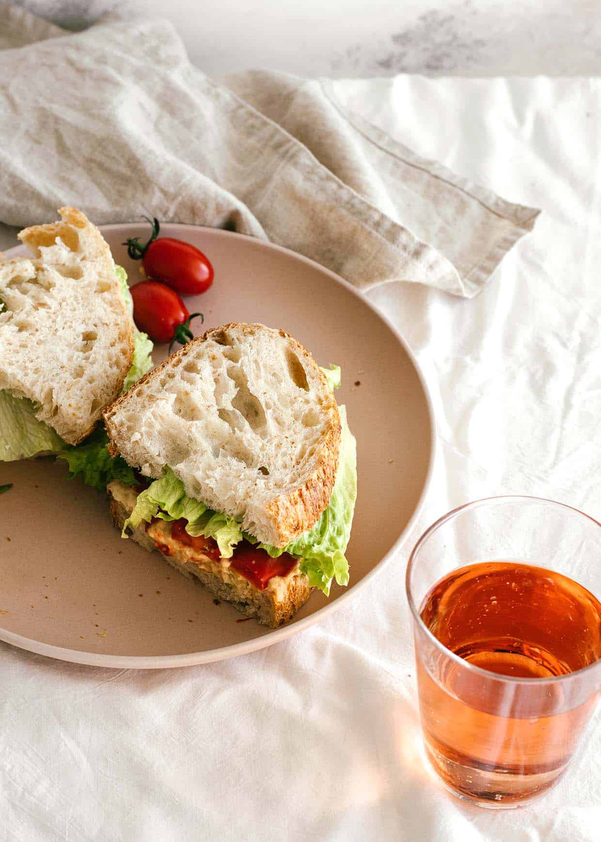 chickpea tuna sandwich on plate with wine on the side