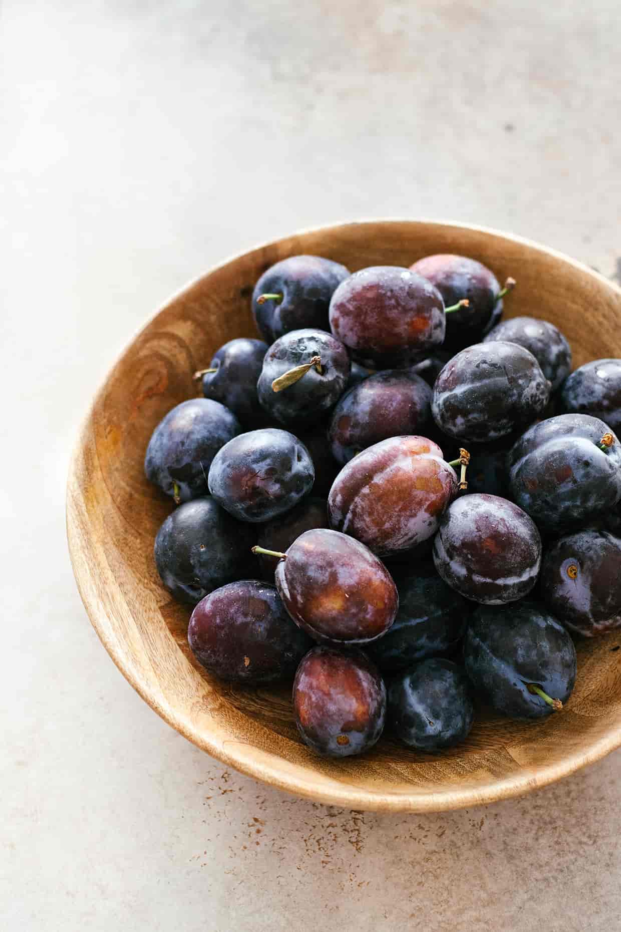 purple italian plums in a wooden bowl