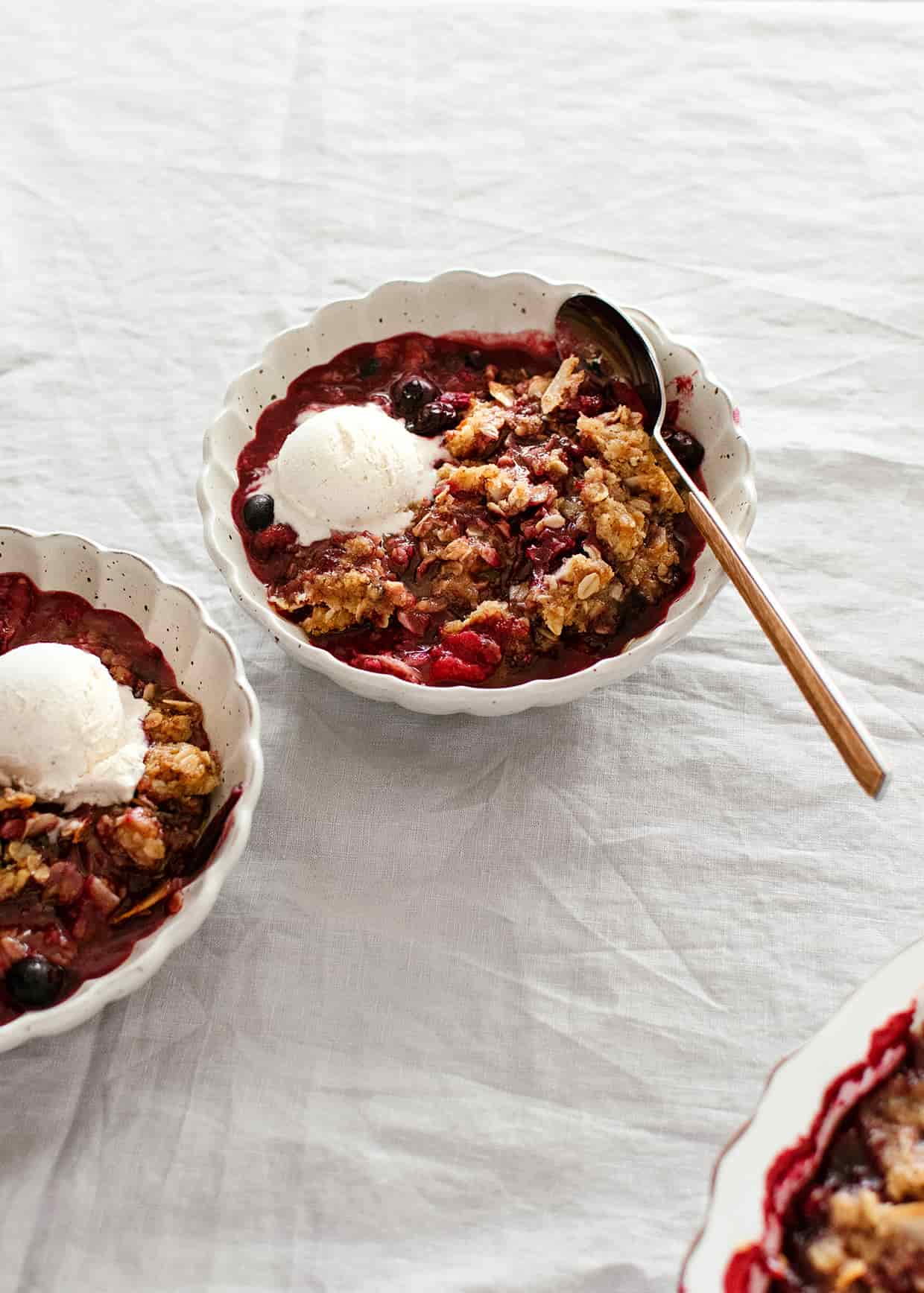 plum crisp served in a bowl with ice cream on top