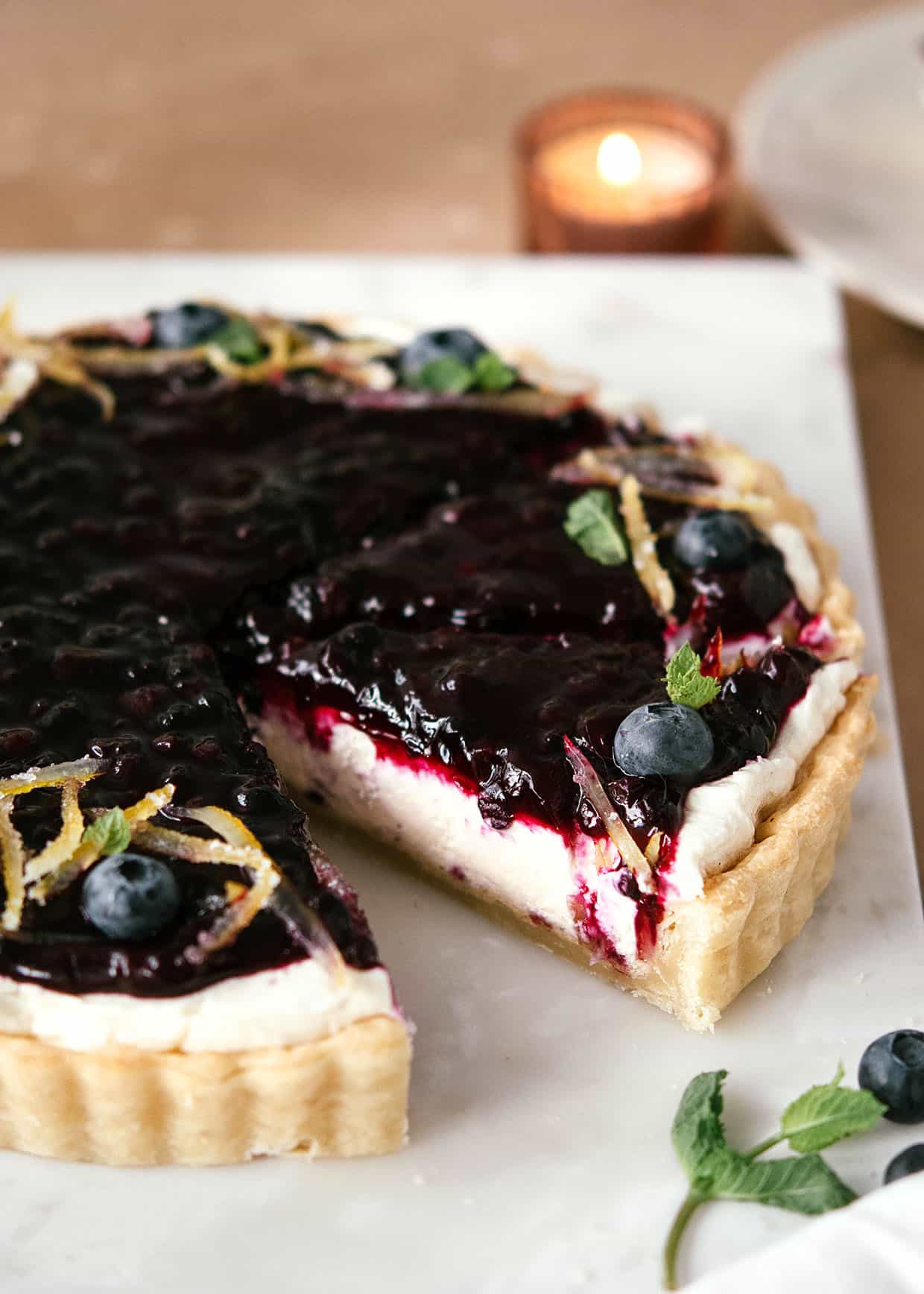 close view of sliced mascarpone tart with blueberry topping