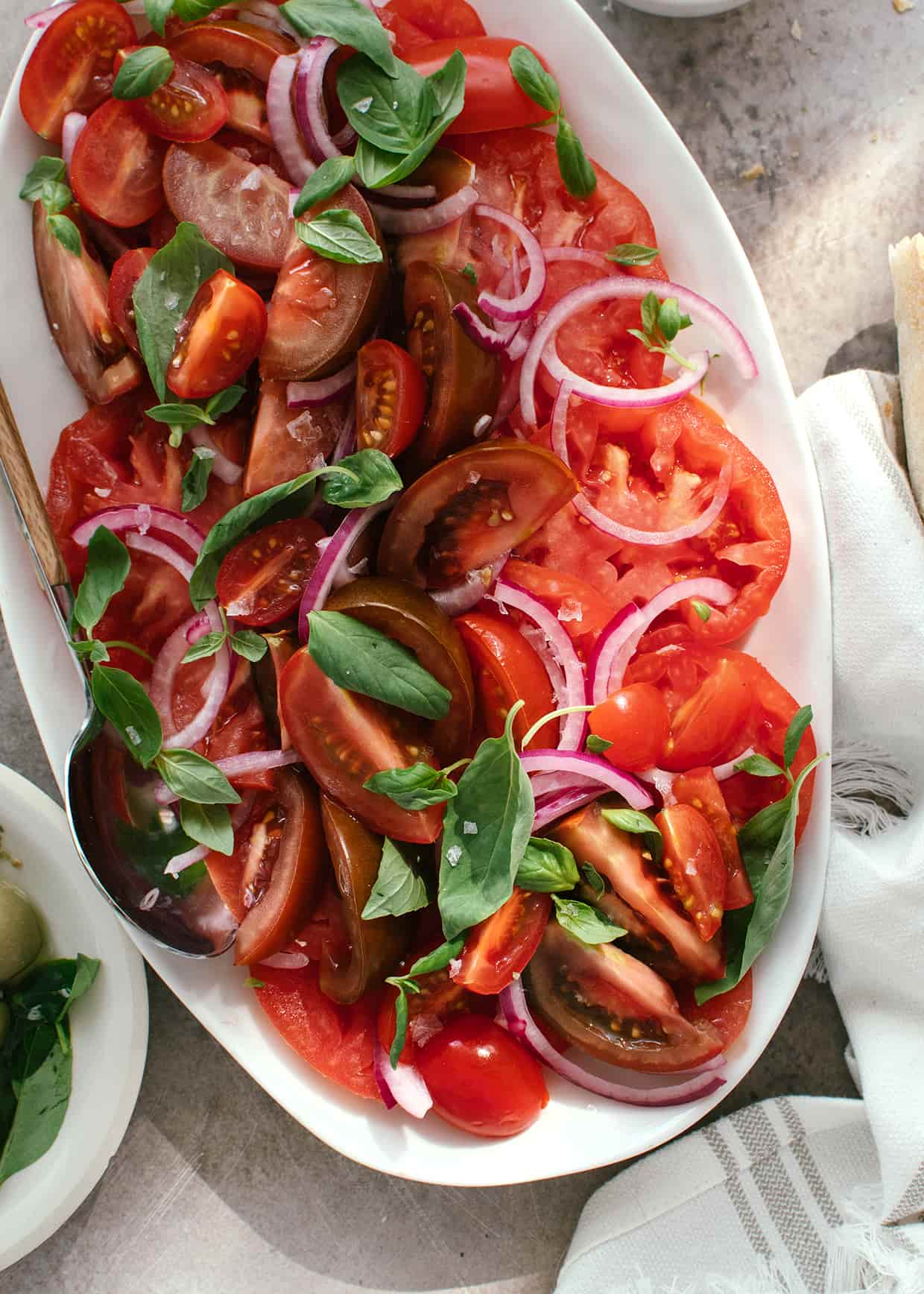 close view of sliced tomato salad with red onions and basil