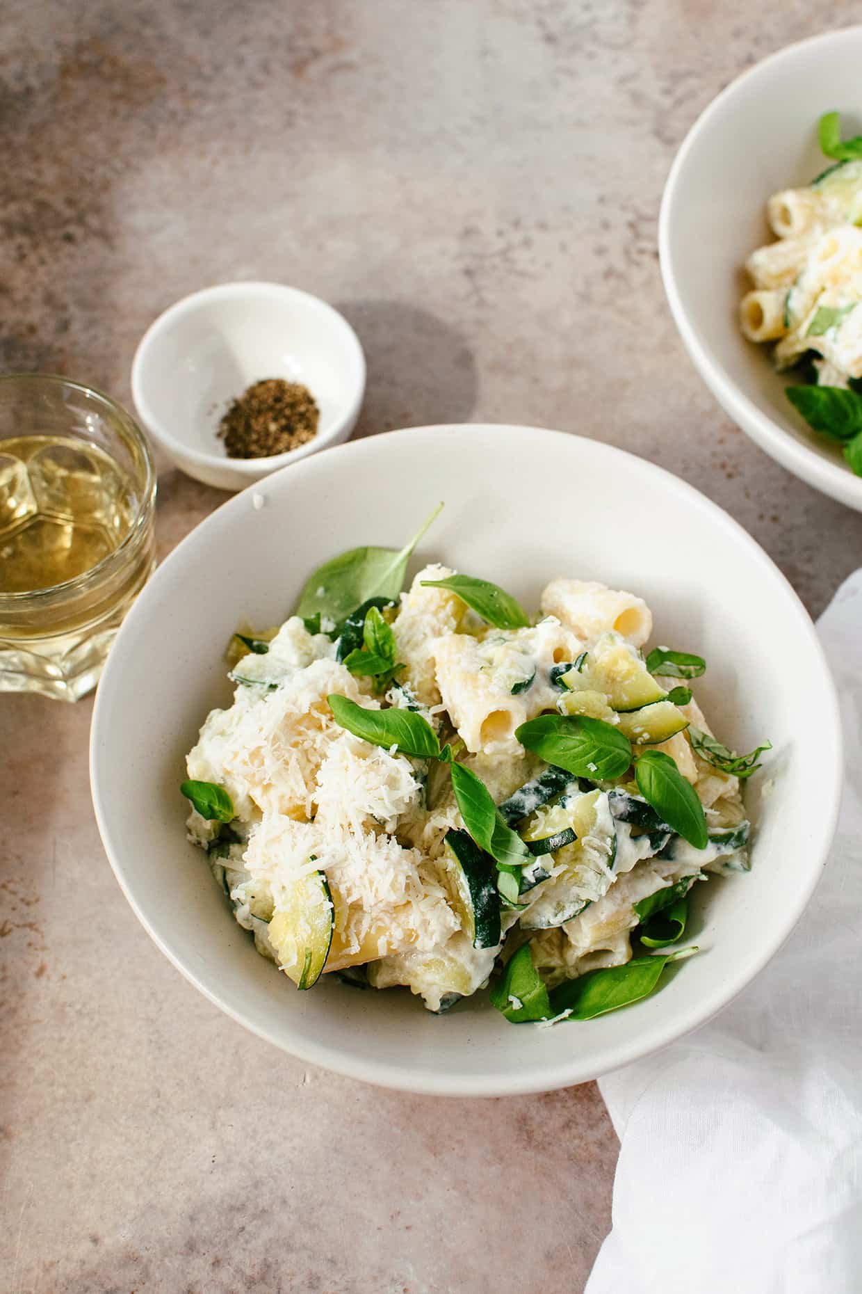 serving bowl with ricotta pasta with basil and wine in a glass next to it