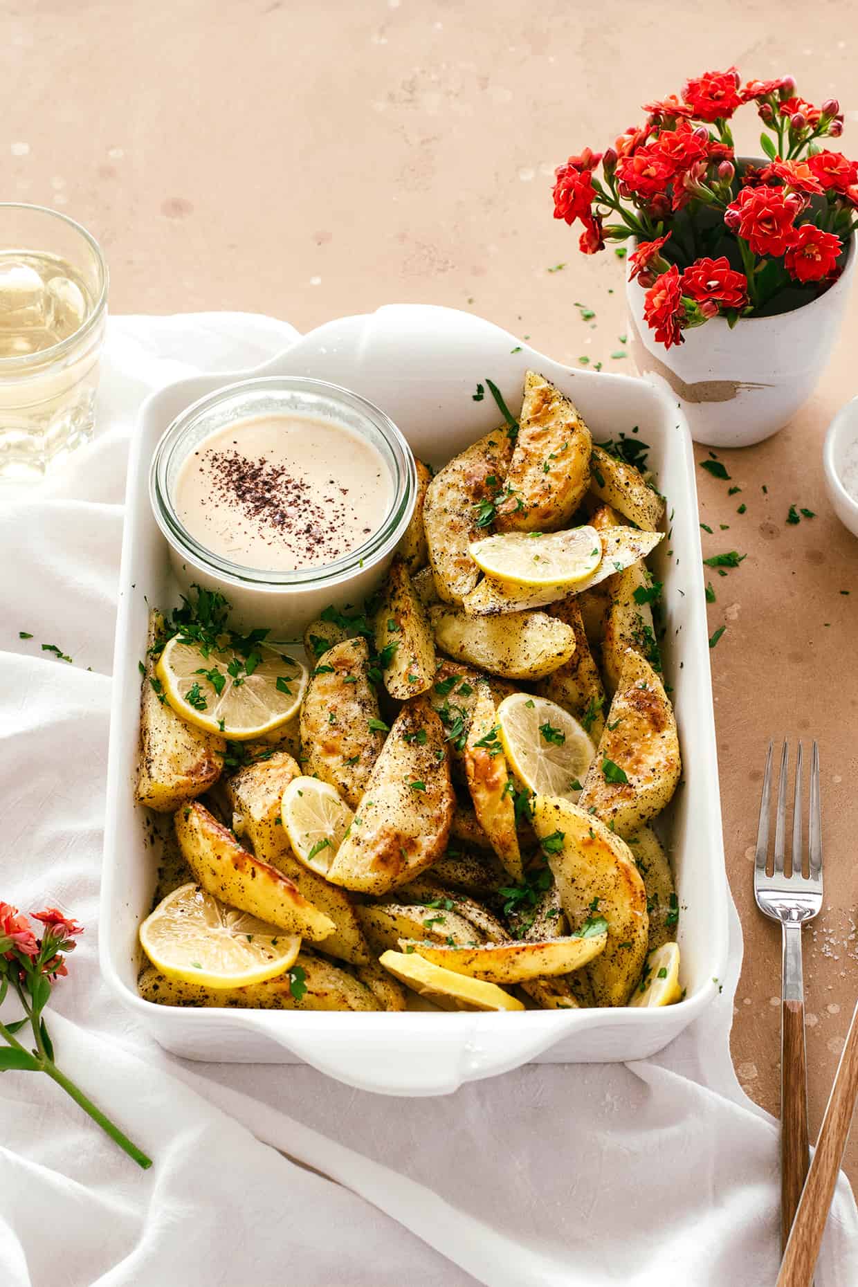 baked potatoes with lemons and parsley served in a baking dish