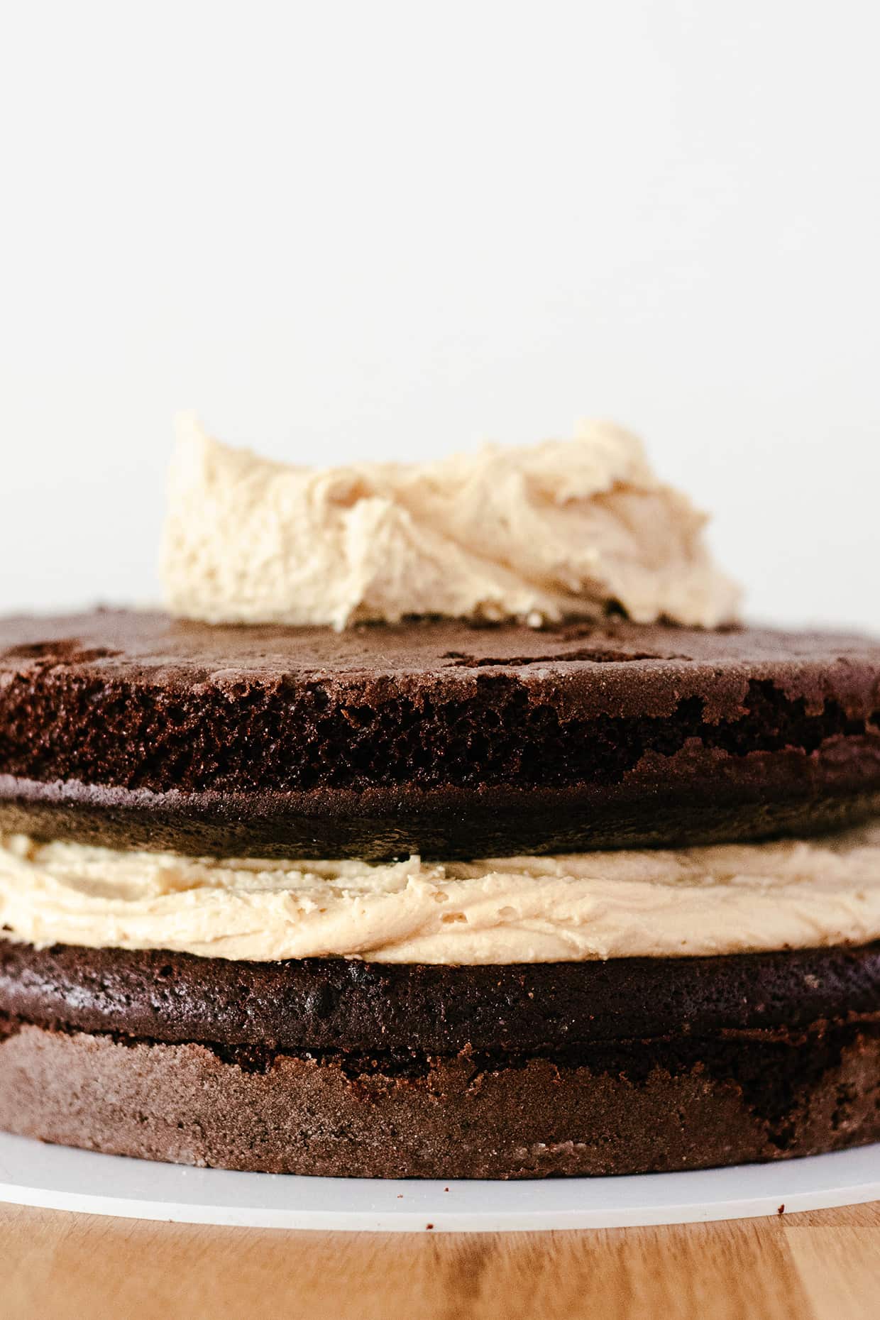 side view of chocolate cake layers and beige peanut butter frosting partially spread out