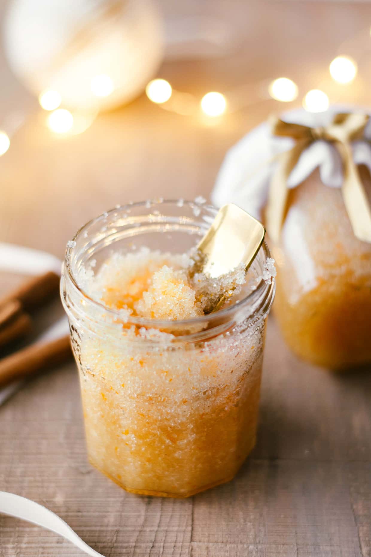 glass jar filled with Cinnamon orange sugar scrub and string lights in the background