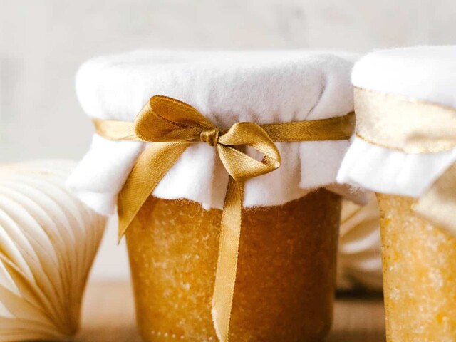 Cinnamon orange sugar scrub in a glass jar wrapped with ribbon