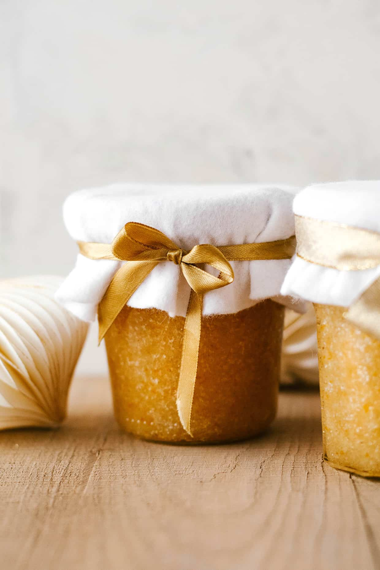 Cinnamon orange sugar scrub in a glass jar wrapped with ribbon