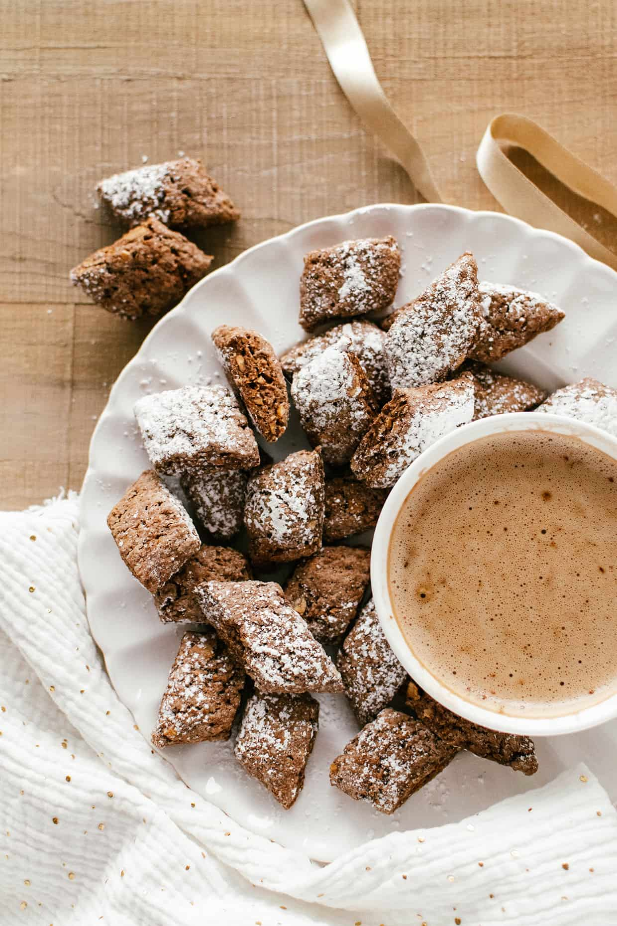 cocoa cookies dusted with sugar on a white plate with cup of hot cocoa on the side