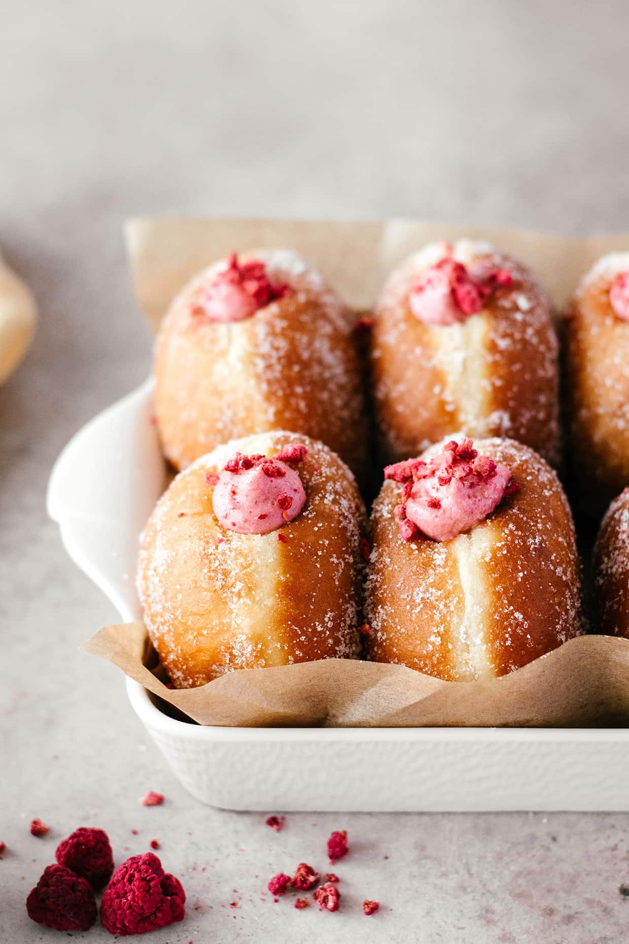 brioche doughnuts with pink raspberry filling served in a white rectangular dish 