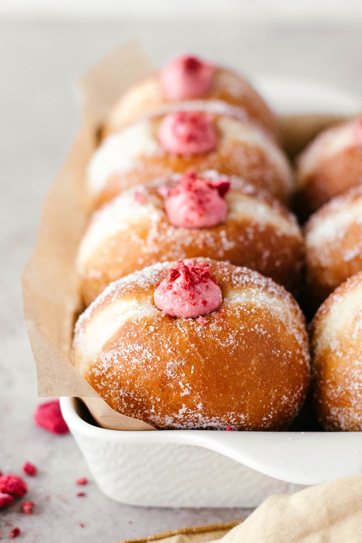 front view of 4 doughnuts lined up in a baking dish with pink filling peaking out