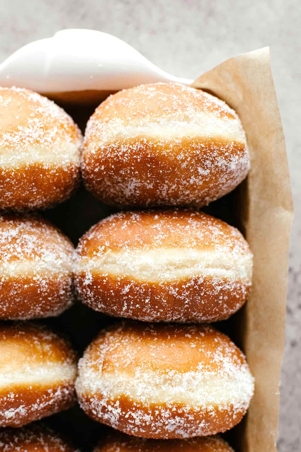 a baking dish filled with fresh fried golden brown doughnuts coated with granulated sugar 