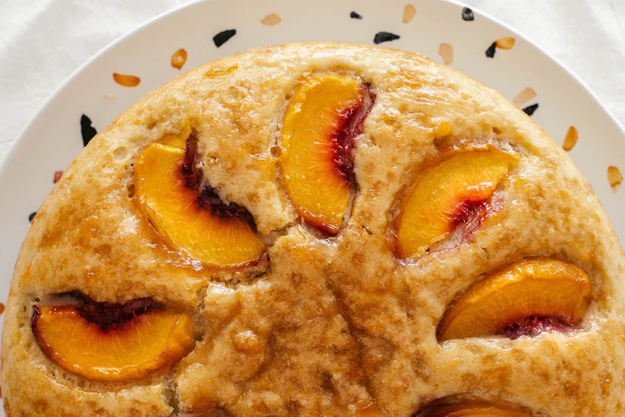 close view of baked peach wedges on top of peach cake