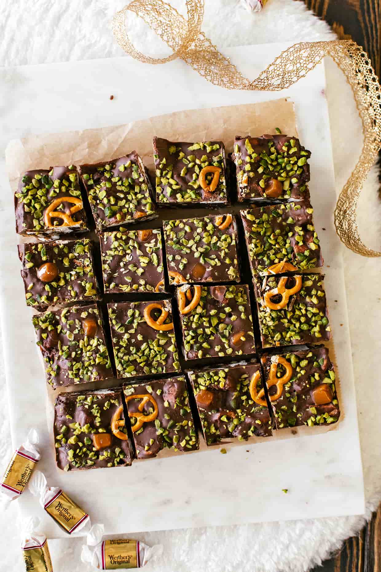 top view of a sliced batch of chocolate rocky road bars, with pretzels and pistachios sprinkled all over