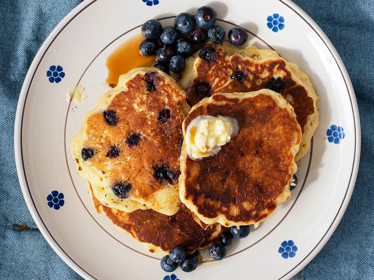 plate with american granola pancakes with blueberries and maple syrup