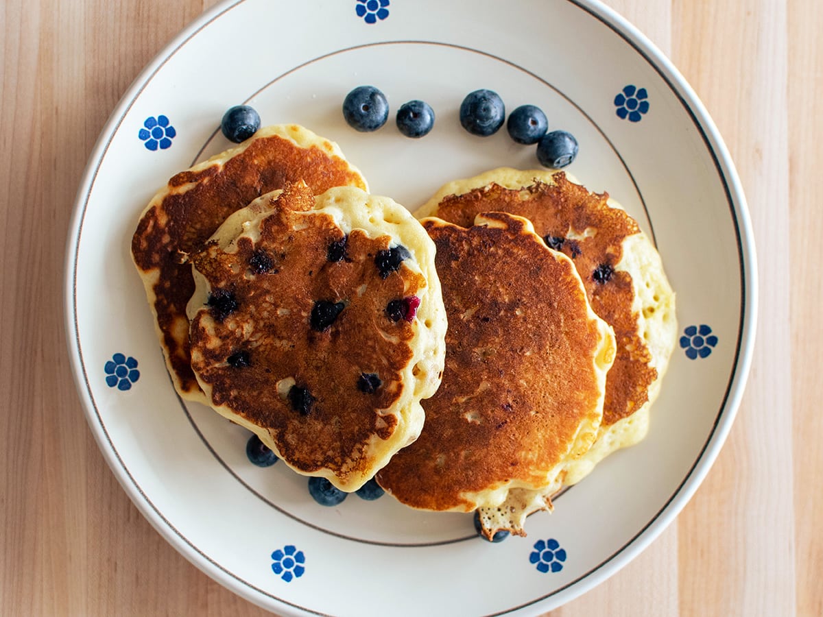 a plate with four fresh blueberry pancakes