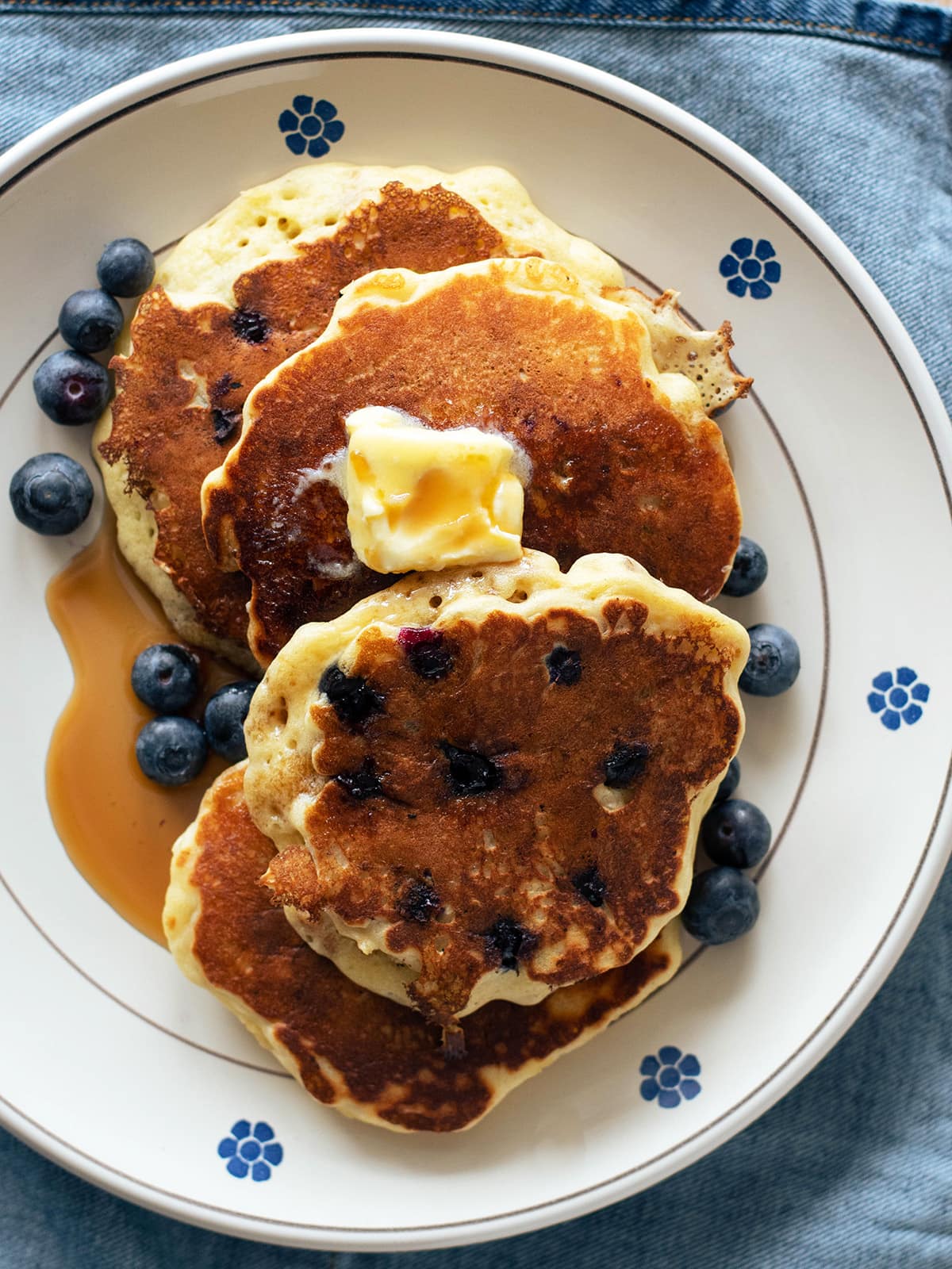 a plate of pancakes with blueberries and maple syrup